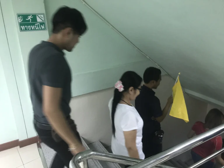 ขบวนพนักงานเคลื่อนที่ผ่านเส้นทางหนีไฟที่มีป้ายบอกทางชัดเจนในระหว่างการฝึกซ้อม Fire Drill โดย TFGC