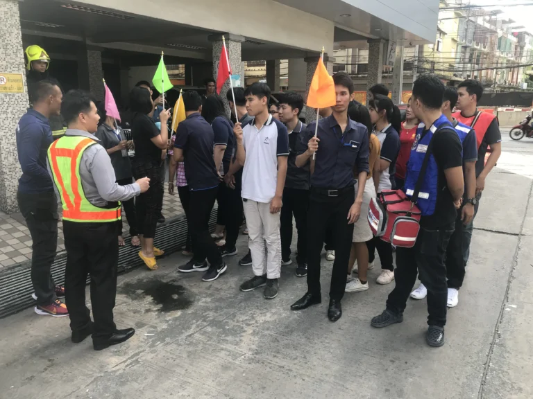 ขบวนพนักงานเคลื่อนที่ผ่านเส้นทางหนีไฟที่มีป้ายบอกทางชัดเจนในระหว่างการฝึกซ้อม Fire Drill โดย TFGC